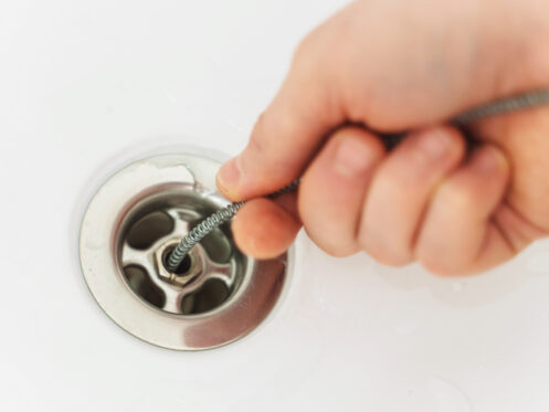 Plumber using a drain snake to clear a drain