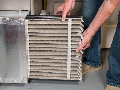 A man changing a dirty air filter in a furnace in Flower Mound, TX